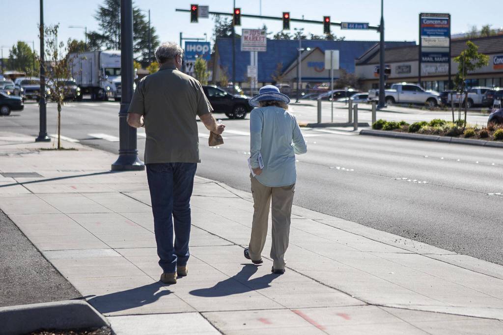 People walk near the 196th and 44th Ave West intersection in Lynnwood, Washington on Tuesday, Aug. 15, 2023. (Annie Barker / The Herald)
