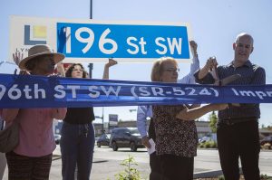 Lynnwood Mayor Christine Frizzell, second from right, and Rep. Rick Larsen, right, cut a ribbon during a ceremony to celebrate the completion of the 196th ST SW Improvement Project near the 196th and 44th Ave West intersection in Lynnwood, Washington on Tuesday, Aug. 15, 2023. (Annie Barker / The Herald)