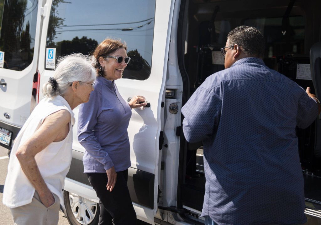 Char McCain, left, U.S. Congresswoman Suzan DelBene, center, and Lloyd White, talk about one of the current Homage transportation vehicles on Monday, Aug. 14, 2023 in Lynnwood, Washington. (Olivia Vanni / The Herald)