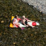Two children float down the Pilchuck River on an inflatable slice of pizza on Sunday, August 13, 2023, in Snohomish, Washington. Inland temperatures look to creep into the 90s during the week. (Ryan Berry / The Herald)