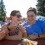 Sisters Nadia, left, and Yasmeen Kabbani dig into some pulled pork tater tots from Ryans REZ-ipes during Taste Edmonds on Saturday, August 12, 2023, at Franceós Anderson Play Field in Edmonds, Washington. (Ryan Berry / The Herald)