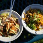 Lentils with pork, left, and vegetable soba saltado from Garzón Latinx Street Food sit on a table during Taste Edmonds on Saturday, August 12, 2023, at Frances Anderson Play Field in Edmonds, Washington. (Ryan Berry / The Herald)