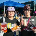 Angelina Kha, left, and Davina Nguyen show off their choices from TeaCo Tea House and Seoul Hotdog during Taste Edmonds on Saturday, August 12, 2023, at Frances Anderson Play Field in Edmonds, Washington. (Ryan Berry / The Herald)