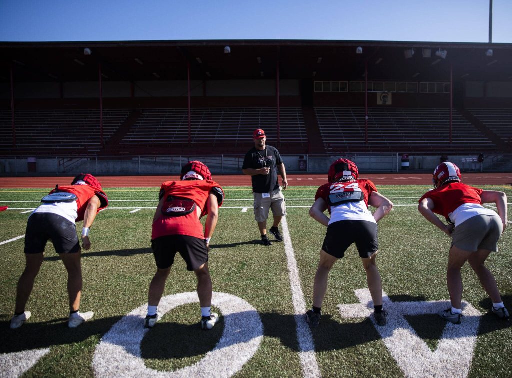 A Stanwood coach runs players through a drill on Friday, Aug. 18, 2023 in Stanwood, Washington. (Olivia Vanni / The Herald)