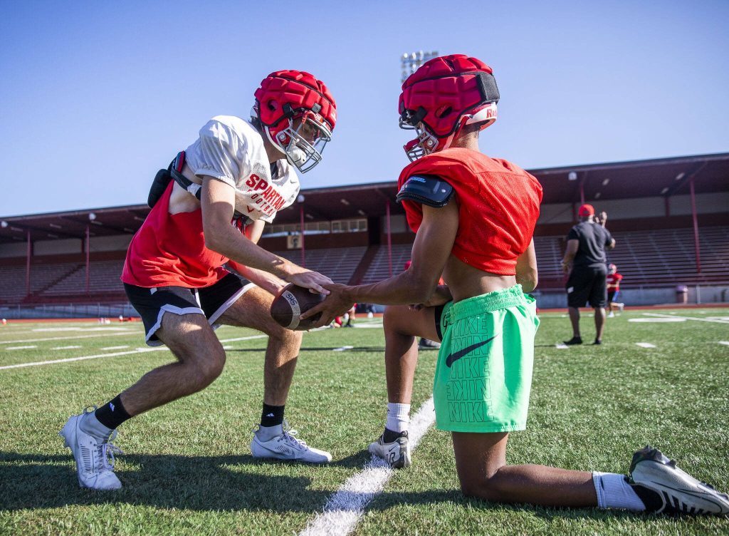Shawn Porter, right, hands off the ball to Luke Brennan on Friday, Aug. 18, 2023 in Stanwood, Washington. (Olivia Vanni / The Herald)