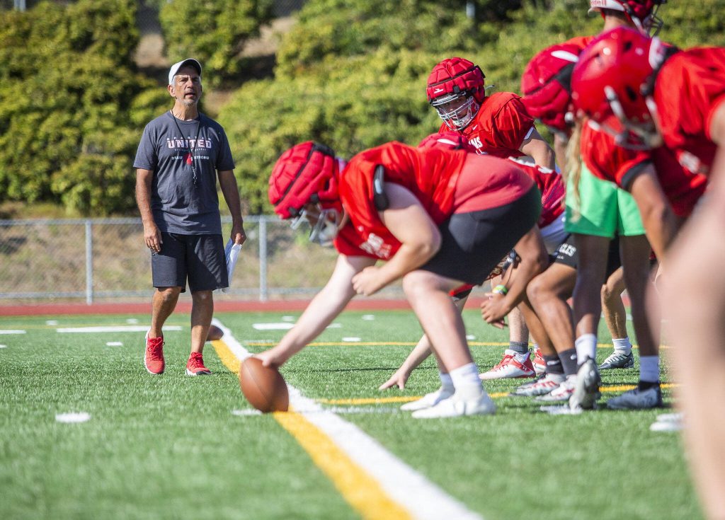 Stanwood head coach Jeff Scoma runs his players through drills during practice Friday in Stanwood. (Olivia Vanni / The Herald)