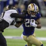 Washington running back Cameron Davis fends off Colorado defensive back Kaylin Moore during a game on Nov. 19, 2022, in Seattle. (AP Photo/Stephen Brashear)