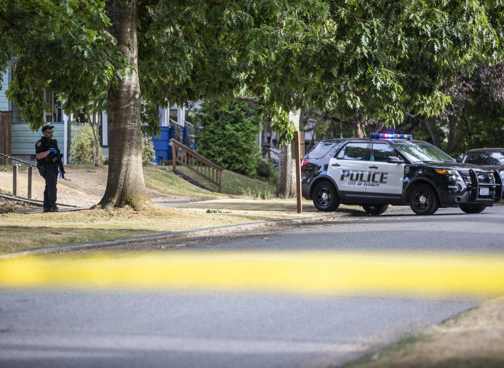An Everett police officer stands across the street from a home surrounded by crime scene tape along Baker Avenue on Tuesday, Aug. 22, 2023 in Everett, Washington. (Olivia Vanni / The Herald)