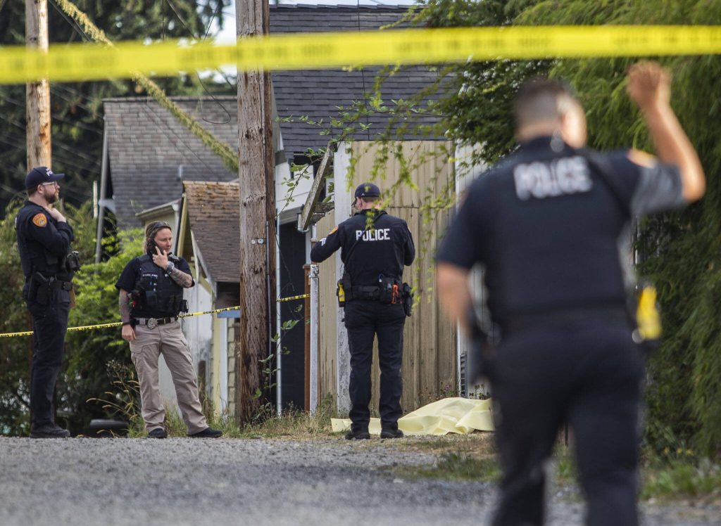 A police officer crosses underneath crime scene tape while walking toward a body in an alleyway on Tuesday, Aug. 22, 2023 in Everett, Washington. (Olivia Vanni / The Herald)