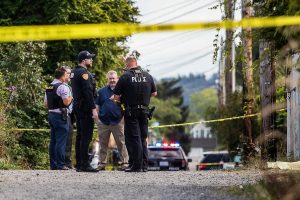 Everett police officers stand in the alley between Virgina Avenue and Baker Avenue next to a body covered in a sheet on Tuesday, Aug. 22, 2023 in Everett, Washington. (Olivia Vanni / The Herald)