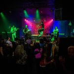 Michael Henrichsen, center, leaps across the stage as people dance during Nite Waves show at Tony Vs Garage on Saturday, June 8, 2019 in Everett, Wash. (Olivia Vanni / The Herald)