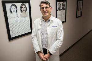 Dr. J. Matthew Lacy along the wall of unsolved cold cases at the Snohomish County Medical Examiner's office on Dec. 4, 2019 in Everett, Wash. (Olivia Vanni / The Herald)