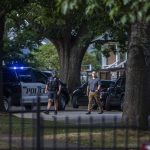 Everett police officers survey the scene in front of homes on the 2300 block of Virgina Avenue on Aug. 22, 2023 in Everett, Washington. (Olivia Vanni / The Herald)