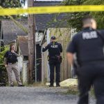 A police officer crosses underneath crime scene tape while walking toward a body in an alleyway on Aug. 22, 2023 in Everett, Washington. (Olivia Vanni / The Herald)