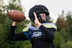 Jacoby Falor smiles while throwing the ball during practice at Arlington High School on Wednesday, Aug. 23, 2023 in Arlington, Washington. (Olivia Vanni / The Herald)