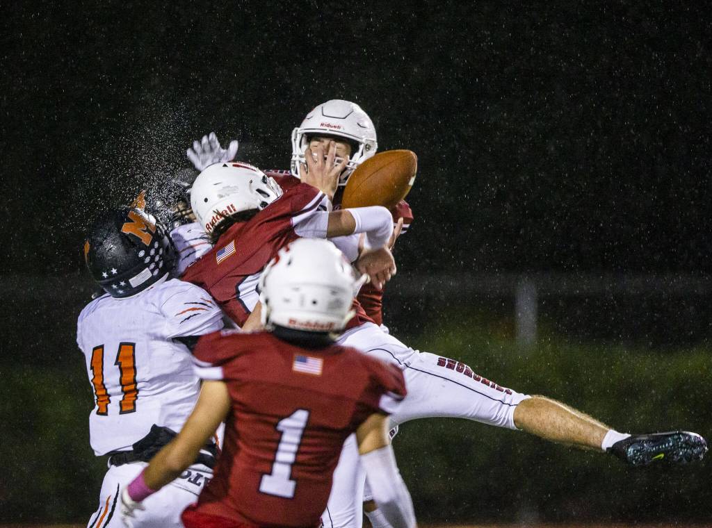 Water sprays as multiple player leap in the air for the ball during a game between Snohomish and Monroe on Oct. 21, 2022, in Snohomish. (Olivia Vanni / The Herald)