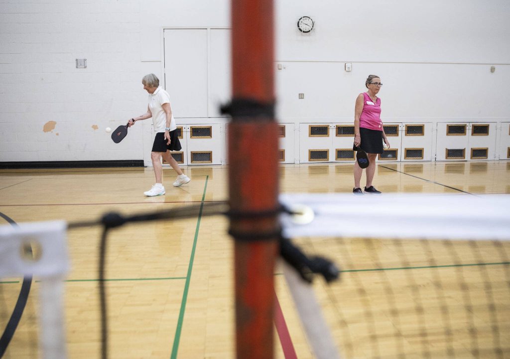 Mary Davis, left, serves the ball while Mary Jane Goss, right, waits for a return during practice matches on Monday, July 31, 2023 in Edmonds, Washington. (Olivia Vanni / The Herald)