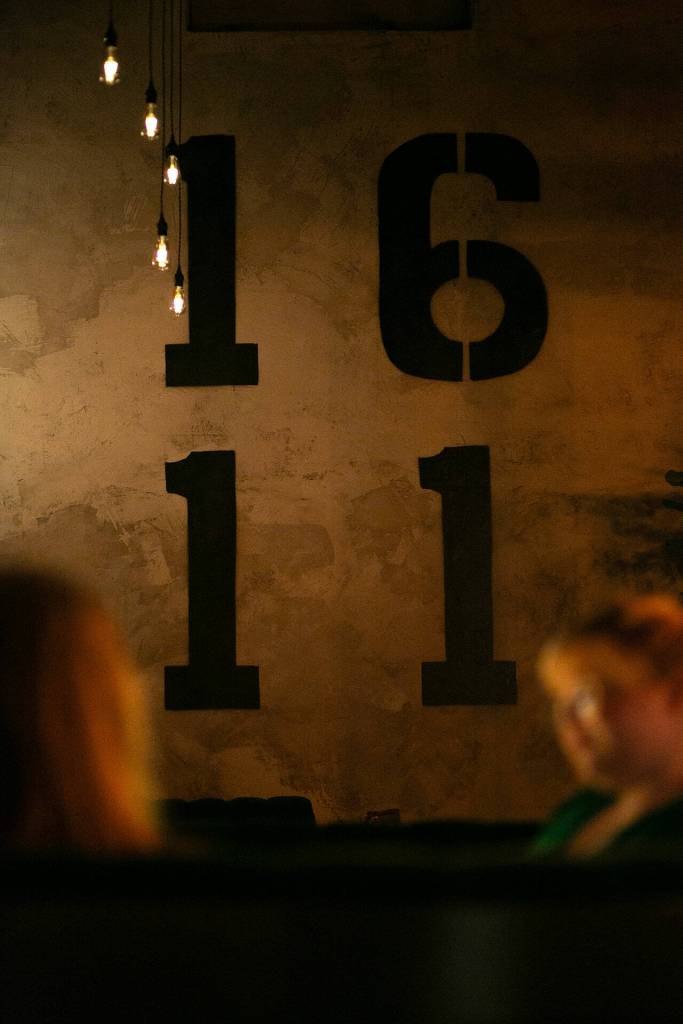 1611 is printed on the wall beyond a table at 16Eleven on Wednesday, August 23, 2023, in downtown Everett, Washington. (Ryan Berry / The Herald)