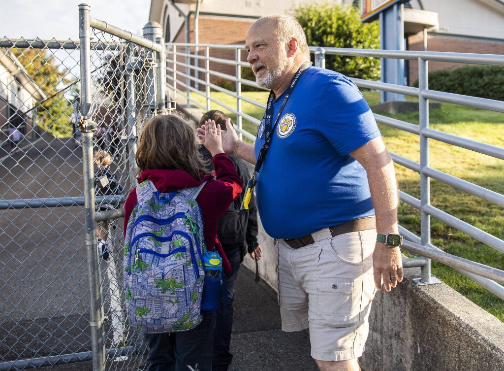 Whittier Elementary para-educator Ian Strum high-fives students as they walk to their first day of school at Whittier Elementary on Wednesday, Sept. 6, 2023 in Everett, Washington. (Olivia Vanni / The Herald)