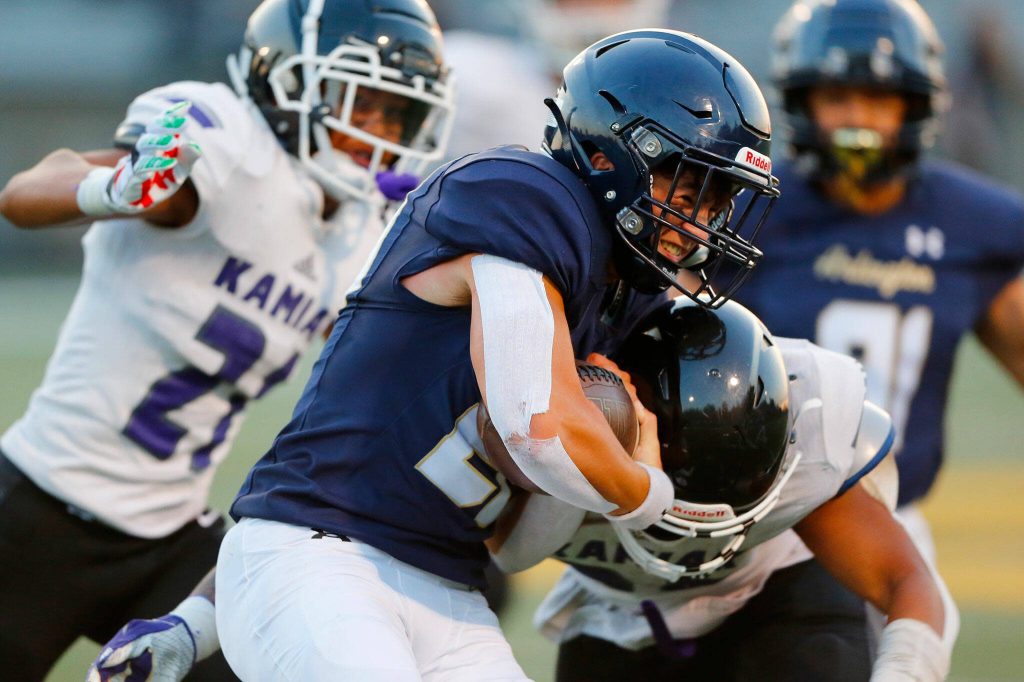 Arlington junior running back Caleb Reed takes a hit after collecting a first down during the season opener against Kamiak on Friday, Sep. 1, 2023, at Arlington High School in Arlington, Washington. (Ryan Berry / The Herald)