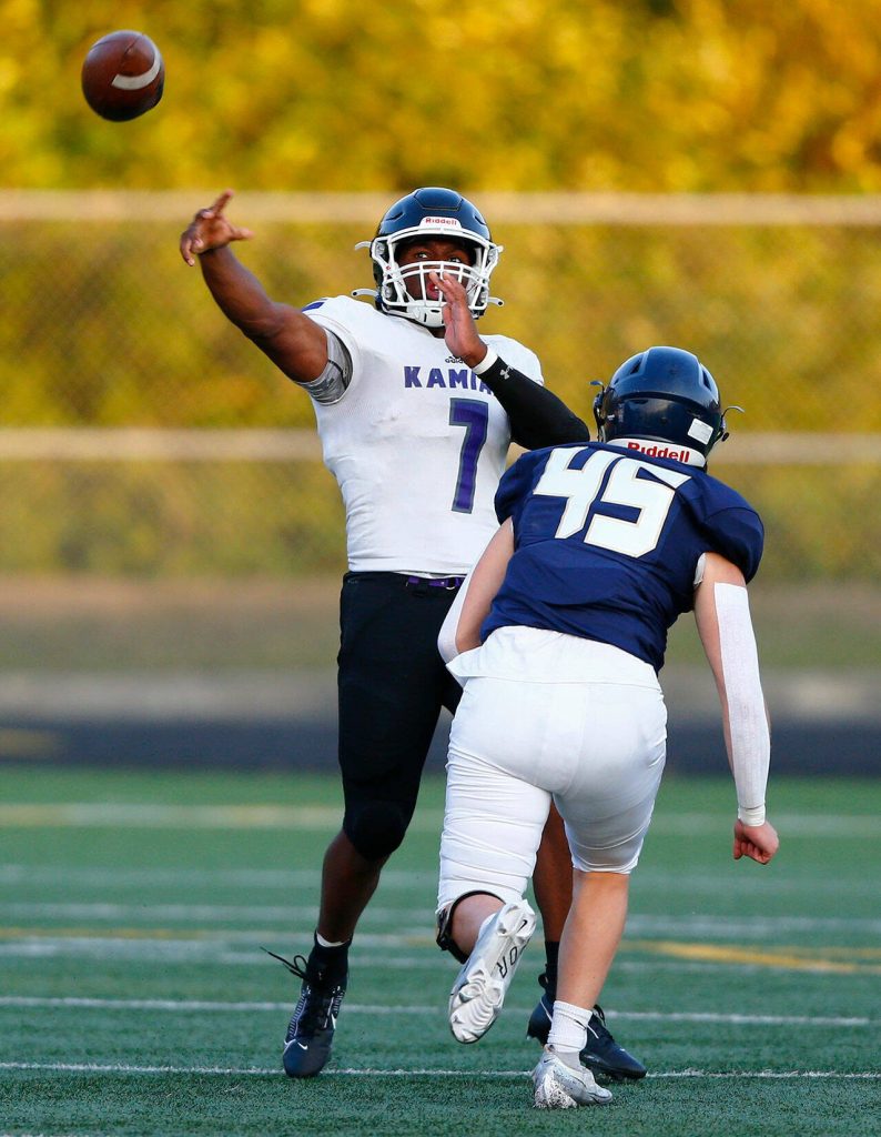 Kamiaks Jericho Ishmael gets rid of a pass before getting hit by Arlington defender Alex Cunningham during the season opener against Arlington on Friday, Sep. 1, 2023, at Arlington High School in Arlington, Washington. (Ryan Berry / The Herald)