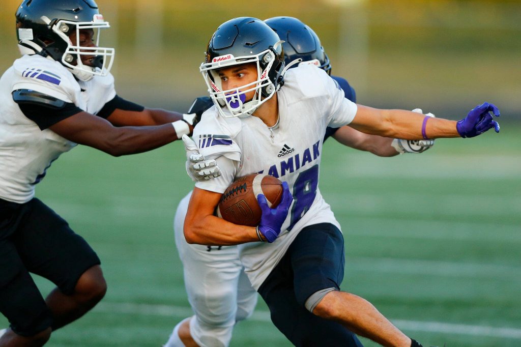 A Kamiak receiver slips by one defender before being taken down during the season opener against Arlington on Friday, Sep. 1, 2023, at Arlington High School in Arlington, Washington. (Ryan Berry / The Herald)