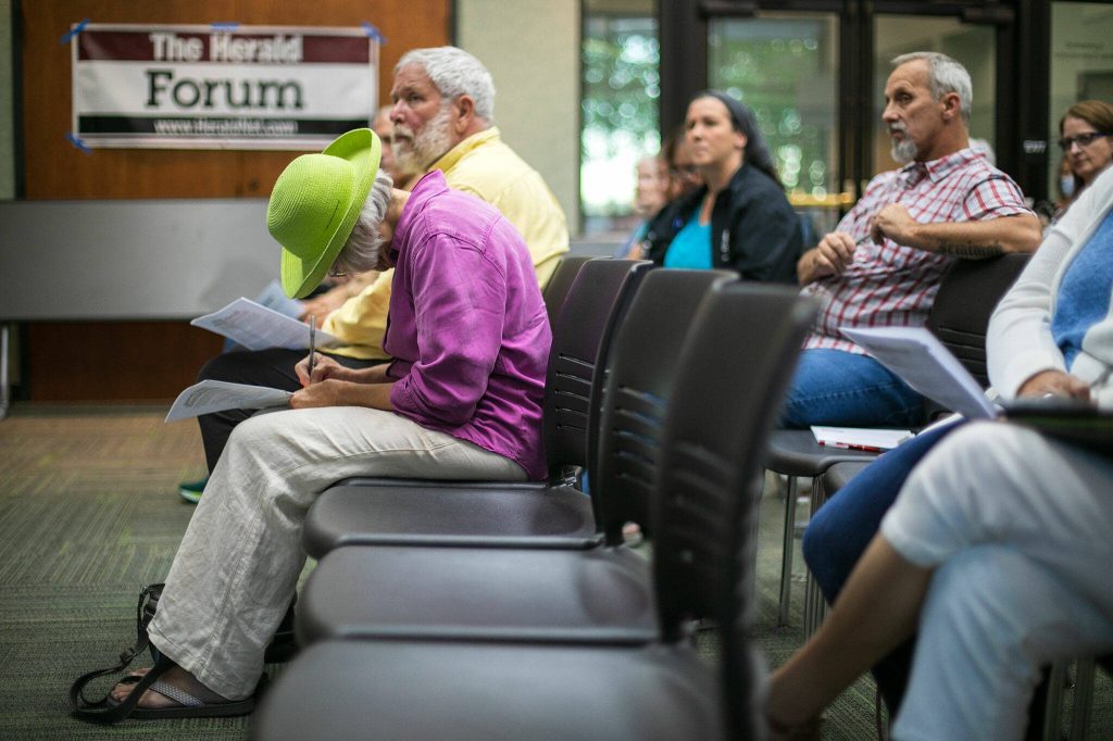 A member of the audience writes down a question while listening to the discussion during the Everett Heralds public forum on affordable housing at the Lynnwood Library on Thursday, Sept. 14, 2023, in Lynnwood, Washington. (Ryan Berry / The Herald)