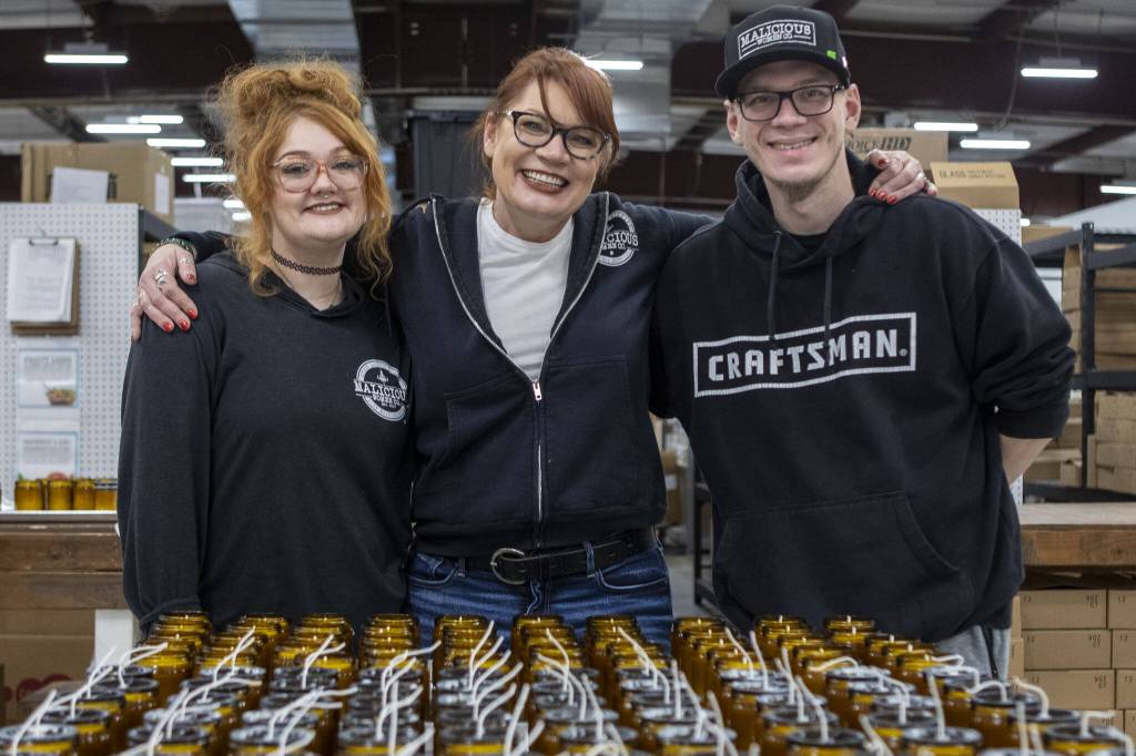 Left to right, creative director Kacie Kicinski, owner and CEO Lacie Carroll, and logistics manager Joe Kicinski, pose for a photo at the Malicious Women Candle Co workspace in Snohomish, Washington on Wednesday, Feb. 15, 2023. The business is women run and owned. (Annie Barker / The Herald)