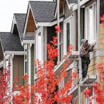 A construction worker caulks the siding on a townhouse at The Towns at Riverfront housing development in Everett on October 25, 2017. (Kevin Clark / The Herald)