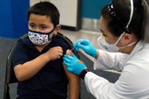FILE - Six-year-old Eric Aviles receives the Pfizer COVID-19 vaccine from pharmacist Sylvia Uong at a pediatric vaccine clinic for children ages 5 to 11 set up at Willard Intermediate School in Santa Ana, Calif., Tuesday, Nov. 9, 2021. In a statement Sunday, Nov. 28, 2021, California's public health officer, Dr. Tomas J. Aragon, said that officials are monitoring the Omicron variant. There are no reports to date of the variant in California, the statement said. Aragon said the state was focusing on ensuring its residents have access to vaccines and booster shots. (AP Photo/Jae C. Hong, File)