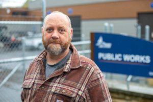Mike Bredstrand, who is trying to get back his job with Lake Stevens Public Works, stands in front of the department’s building on Wednesday, Sept. 27, 2023, in Lake Stevens, Washington. Bredstrand believes his firing in July was an unwarranted act of revenge by the city. (Ryan Berry / The Herald)