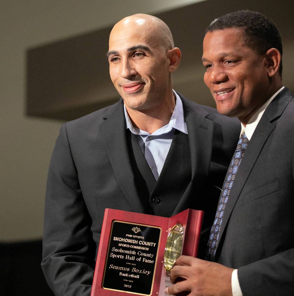 Hall of Fame inductee Seamus Boxley, left, accepts his award with keynote speaker Donald Watts during the 2023 Snohomish County Sports Hall of Fame Banquet on Wednesday, Sept. 27, 2023, at Angel of the Winds Arena in Everett, Washington. (Ryan Berry / The Herald)