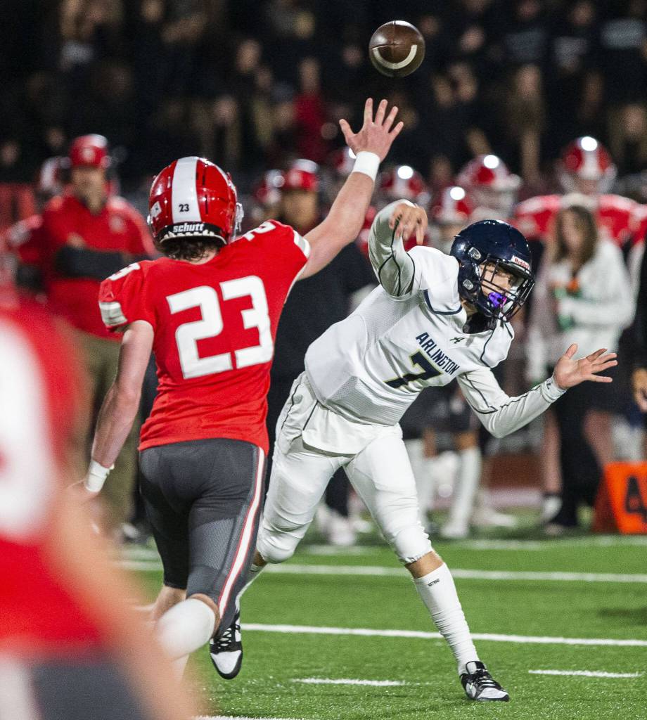 Arlingtons Leyton Martin throws the ball above the extended arm of Stanwoods Ethan Burke during the game on Friday, Sept. 29, 2023 in Stanwood, Washington. (Olivia Vanni / The Herald)