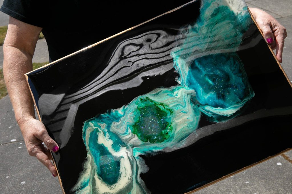 Downes displays the reflective properties of her resin art. (Ryan Berry / The Herald)