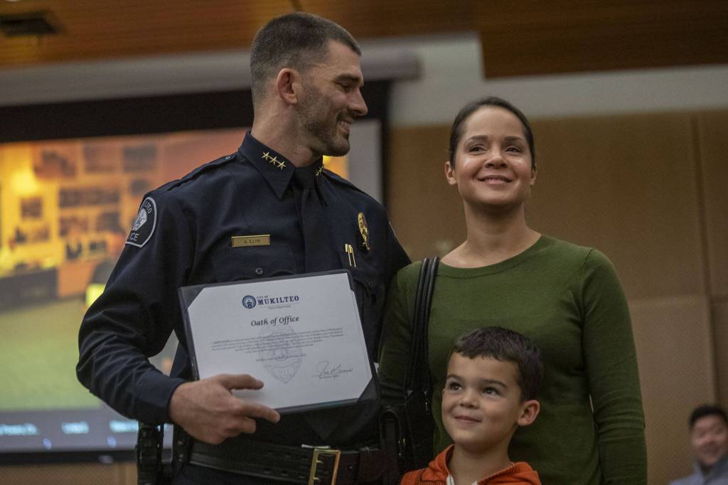 Andy Illyn, left, poses for a photo with his wife, Tiffany, right, and their son, Phoenix, after being sworn in as the new Mukilteo Police Chief at Mukilteo City Hall on Monday, Oct. 2, 2023. (Annie Barker / The Herald)