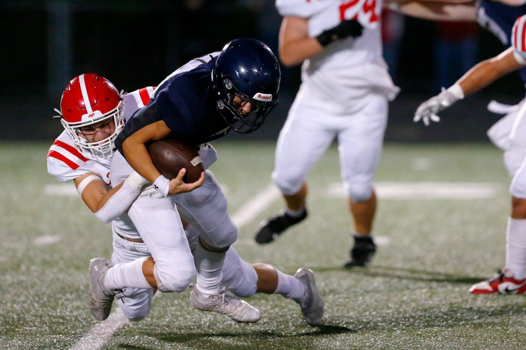 Arlington running back Caleb Reed is taken down behind the line by Marysville Pilchuck senior Shane Nelson on Friday, Oct. 6, 2023, at Arlington High School in Arlington, Washington. (Ryan Berry / The Herald)