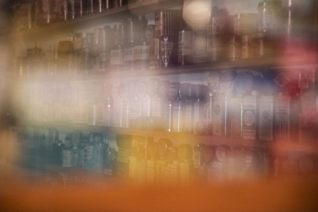 Shelves of tins are reflected off a shadow box filled with smaller tins. (Olivia Vanni / The Herald)