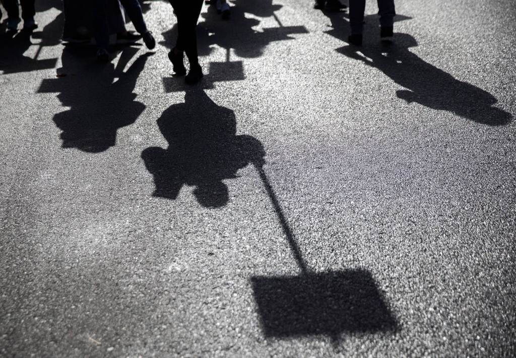 Everett Public Schools paraeducators shadows are cast on the ground as they protest on Tuesday, Oct. 10, 2023 in Everett, Washington. (Olivia Vanni / The Herald)