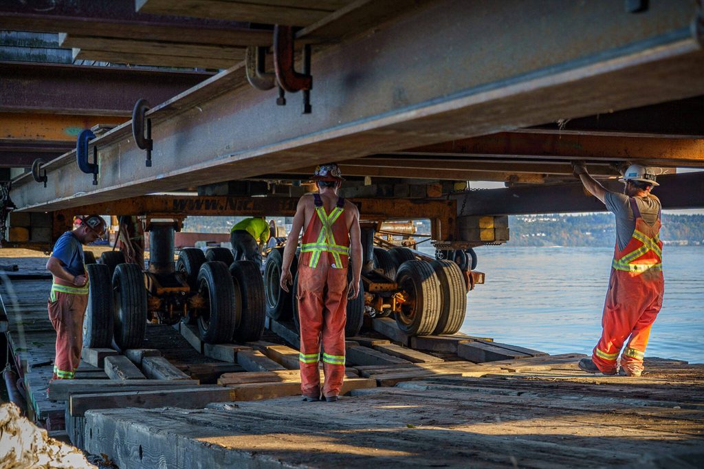 Workers venture under the house as it is placed on a truck. (Photo by David Welton)