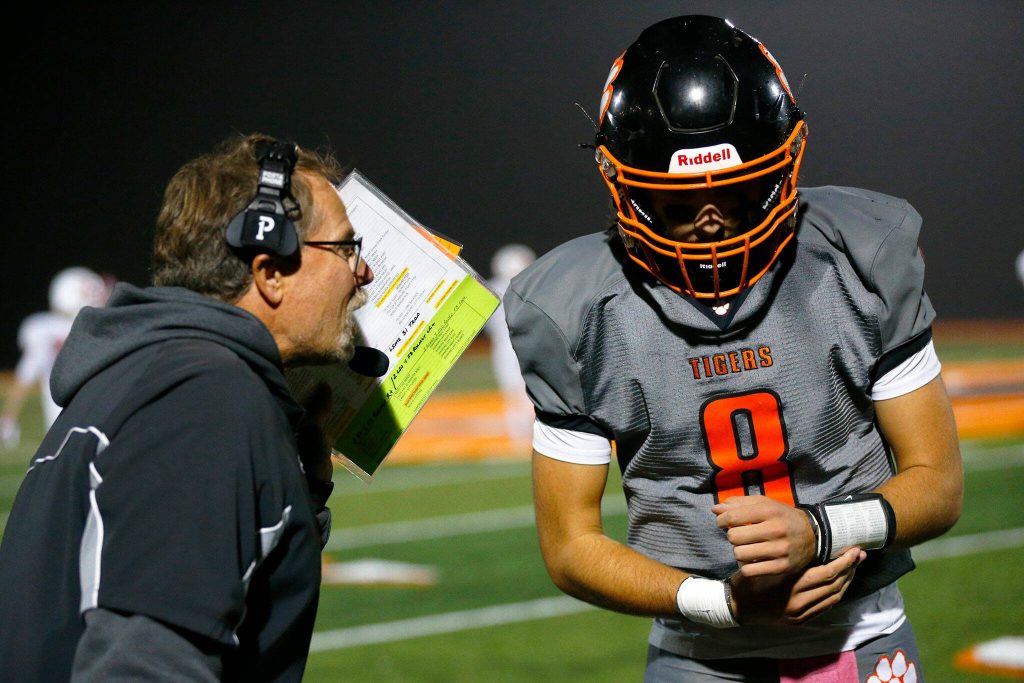 Granite Falls quarterback Kaden LaPlaunt gets the call from his coach during a game against Kings on Friday, Oct. 20, 2023, at Granite Falls High School in Granite Falls, Washington. (Ryan Berry / The Herald)