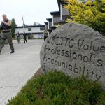 Cadets LeAnne Cone, left, of the Vancouver Police Dept., and Kevin Burton-Crow, right, of the Thurston Co. Sheriffs Dept., walk past a rock at the Washington state Criminal Justice Training Commission engraved with WSCJTC Values Professionalism, Accountability Integrity, on the way to a training exercise Wednesday, July 14, 2021, in Burien, Washington. (AP Photo/Ted S. Warren)