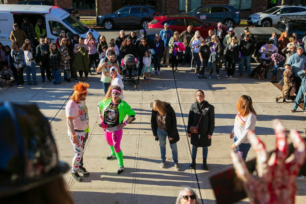 A group of adult contestants compete in a zombie-off while surrounded by a large crowd during the 10th annual Snohomish Zombie Walk on Saturday, Oct. 28, 2023, in downtown Snohomish, Washington. (Ryan Berry / The Herald)