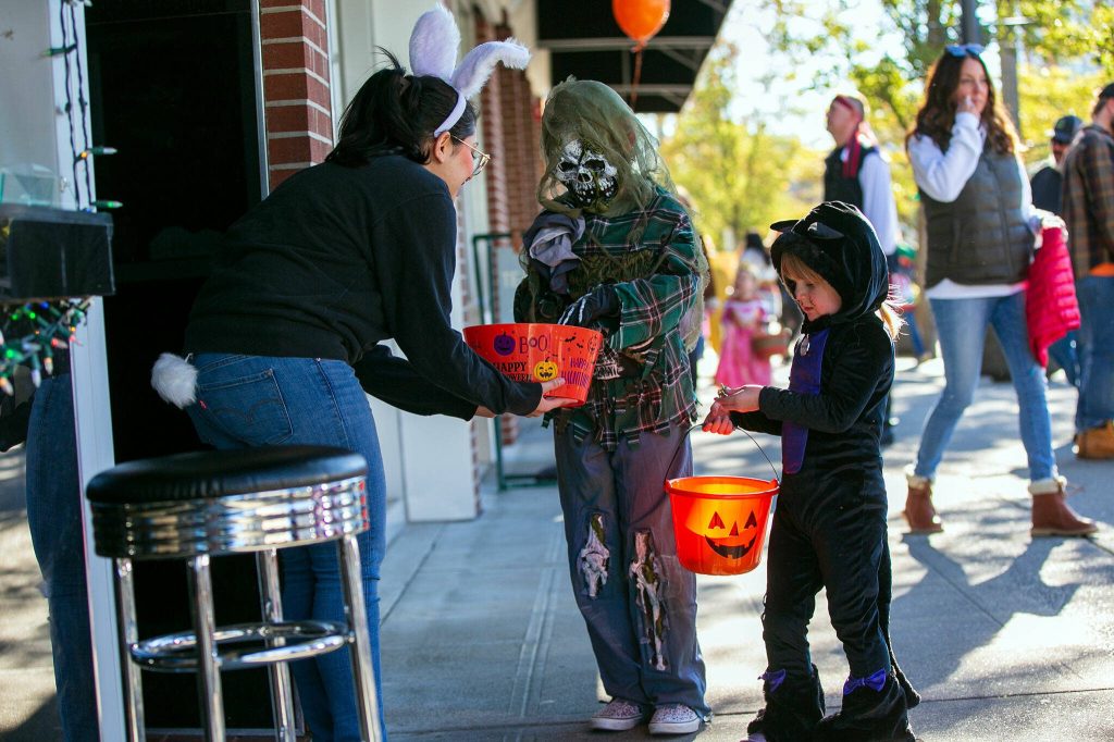 Dinah Zengilou from Botan Ramen n Bar hands out candy during Downtown Everett Associations trick-or-treat event Saturday, Oct. 28, 2023, in Everett, Washington. (Ryan Berry / The Herald)
