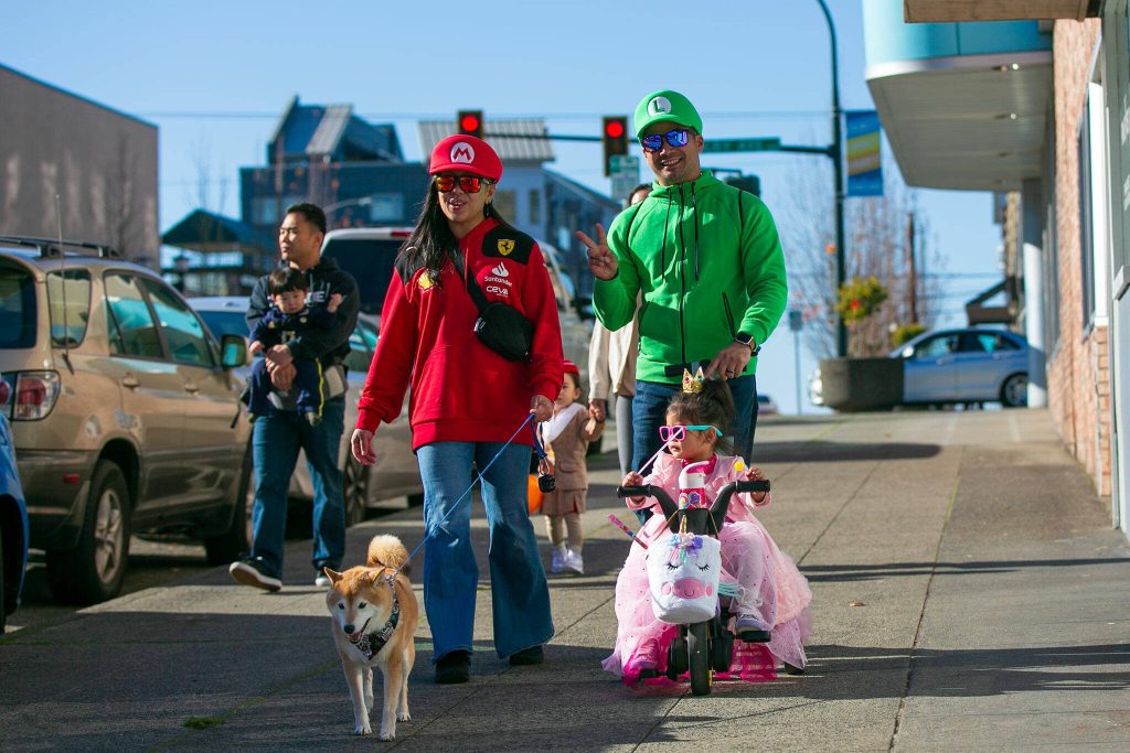 A family of Mario characters heads downtown during Downtown Everett Association’s trick-or-treat event Saturday, Oct. 28, 2023, in Everett, Washington. (Ryan Berry / The Herald)