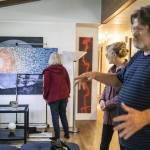 Friends admire a new painting by Sam Taylor during an unveiling he hosted at his home in Everett. The painting is titled A Sunny Day in Everett. (Olivia Vanni / The Herald)