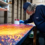 Sam Taylor pops air bubbles in paint while he works on one of his art pieces on Tuesday, Oct. 3, 2023, in Everett, Washington. (Olivia Vanni / The Herald)