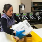 Veteran election worker Tien Mai moves sealed ballots from a sorting machine while working at the Snohomish County Auditor’s office on Friday, Nov. 3, 2023, in downtown Everett, Washington. (Ryan Berry / The Herald)