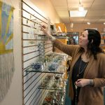 Visual merchandiser April Votolato hangs necklaces as workers at East West Books & Gifts stock shelves during the stores third day in business Friday, Oct. 27, 2023, in Edmonds, Washington. (Ryan Berry / The Herald)