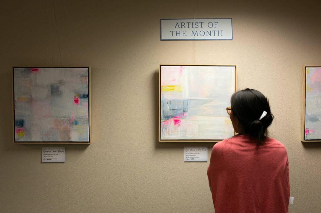 Store manager Rika Rafael looks over guest art at East West Books & Gifts on Friday, Oct. 27, 2023, in Edmonds, Washington. The store plans to rotate through guest artists every three months. (Ryan Berry / The Herald)