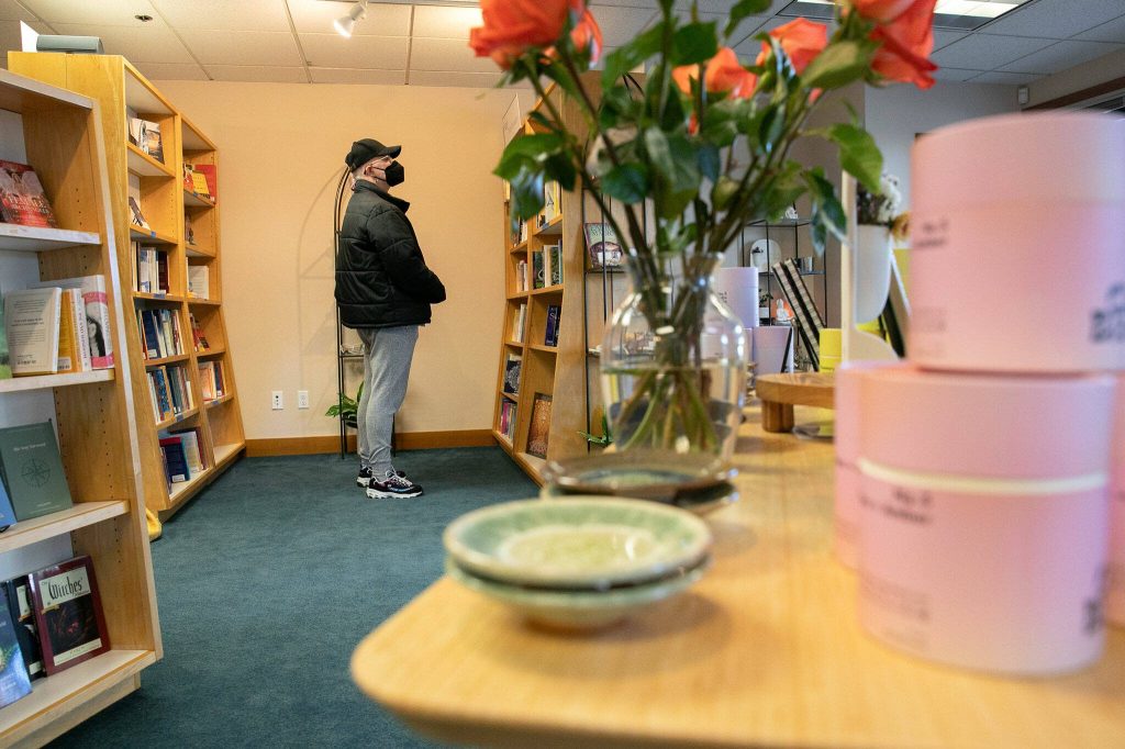 A customer scans the bookshelves at East West Books & Gifts on Friday, Oct. 27, 2023, in Edmonds, Washington. (Ryan Berry / The Herald)